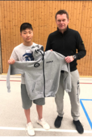 Ziyao bekommt von Roland Rottwilm eine Trainingsjacke überreicht.